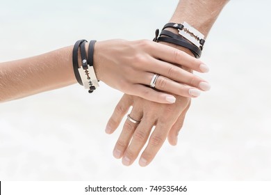 The bride's hand hold the groom's hand. Close up hands with beautiful engagement rings. Style wedding. Fashionable ceremony. Hands with bracelets and blades.  - Shutterstock ID 749535466