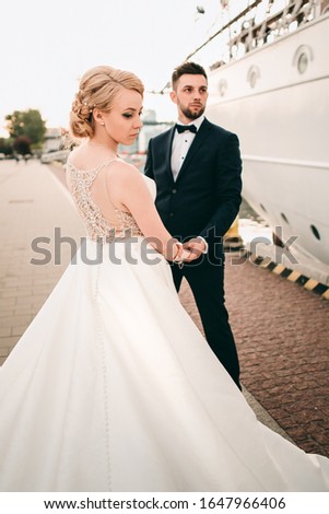 Brides hugging, walking and kissing by the sea near a white ship