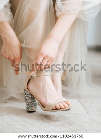 Bride's morning. The bride is putting her shoes on.