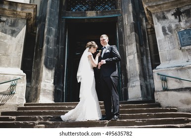 The brides stand on stairs near church