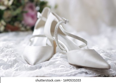 Bride's white wedding shoes and bouquet of flowers close up