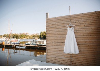 bridesmaid dress hanging on a wooden wall in a yacht club on the background of white yachts - Powered by Shutterstock