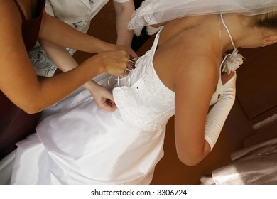 The Bridesmaid And Mum Help The Bride To Tighten A Corset