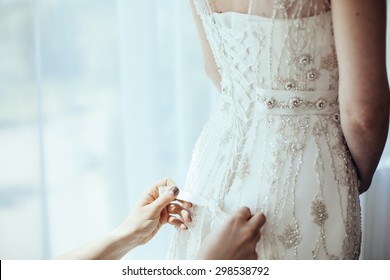 Bridesmaid Tying Bow On Wedding Dress

