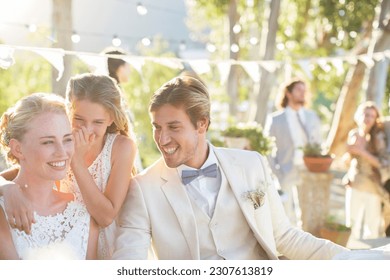 Bridesmaid whispering to bride's ear during wedding reception in domestic garden - Powered by Shutterstock