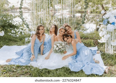 The bridesmaids are in blue dresses, the bride is holding a beautiful bouquet. Sitting enjoying the celebration. Beautiful luxury wedding blog concept. Spring wedding. - Powered by Shutterstock