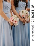 Bridesmaids in blue dresses holding floral arrangements. CLose up of bridal party with bouquets.