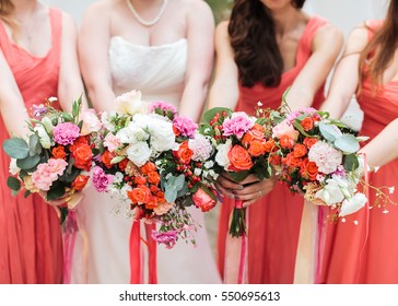 Bridesmaids and bride holds bouquets in hand.