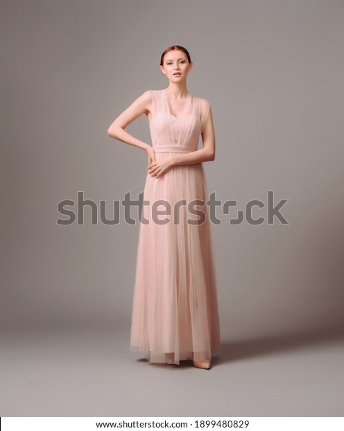 Bridesmaid\'s dresses. Elegant\
moscato dress. Beautiful pink chiffon evening gown. Studio portrait\
of young brunette woman. Transformer dress idea for celebration.\
