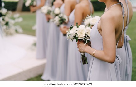 Las damas de honor con vestidos se paran con ramos de flores seguidos