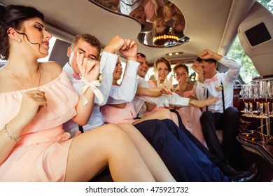 Bridesmaids And Groomsmen Dance While Sitting In The Limousine