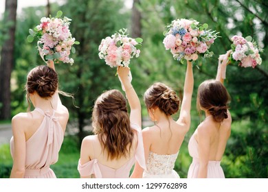 Bridesmaids in pink dresses and bride holding beautiful bouquets. Beautiful luxury wedding blog concept. Summer wedding.