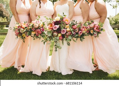 Bridesmaids in Pink Dresses Holding Flower Bouquets Outdoors