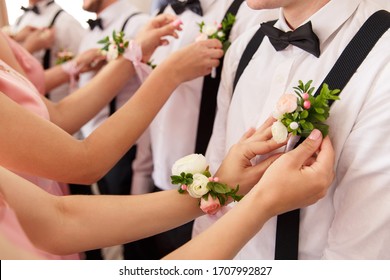 Bridesmaids put small bouquets on shirt of groomsmen at wedding day