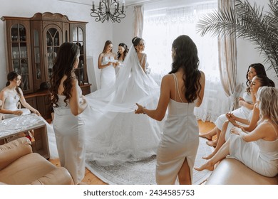 Bridesmaids rejoice in the morning, helping to fasten the buttons on the wedding dress and prepare for the wedding ceremony. They take pictures, smile, help the bride with her shoes. - Powered by Shutterstock