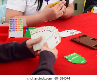  Bridge card game on the red table,  with binding box on their side. Tournament in the school and play sport for fun.