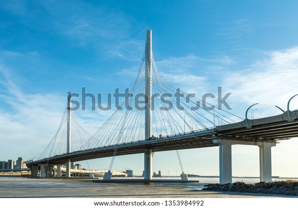 The bridge of\
circle highway road over Neva river near the mouth of it in the\
clear day. The winter landscape of the river covered with ice and\
snow and with the sky with\
clouds