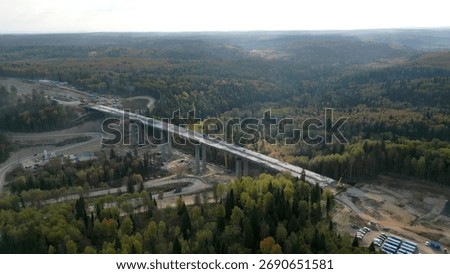Bridge construction progressing over forest landscape. Clip