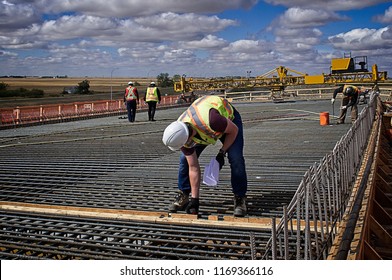 A bridge engineer inspecting spacing diameter   height steel reinforcing bars and tape measure the bridge deck prior to pouring concrete the reinforced deck supported by steel girders