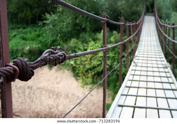 Bridge metal rope connection.\
Bridge across the river. Wooden bridge. Hanging over the river.\
Priekule in the city of Lithuania. The name of the river is\
Minija.
