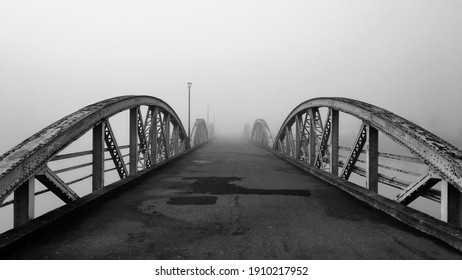 Bridge to nowhere. Black and white old steel bridge road. Monochrome artistic photography. Structure shilouette in foggy weather. Straight line themed image. Urban architecture outdoors.