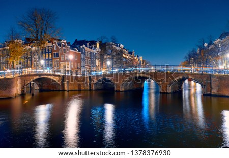 Bridge over the canal and famous brick houses in Amsterdam at night.