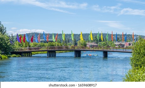 The bridge over the Deschutes River in the Old Mill district of Bend Oregon with colorful flags.