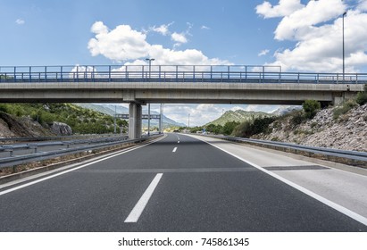 Bridge over a highway on a background of mountains and blue sky.