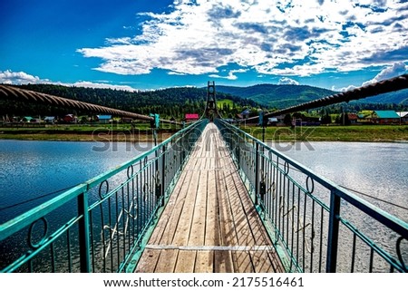 Bridge over the Inzer River in the village of Brishtamak (Bashkortostan, Bashkiria). It leads to a village in a mountainous area, to a mountain village. Nature on a clear sunny day.