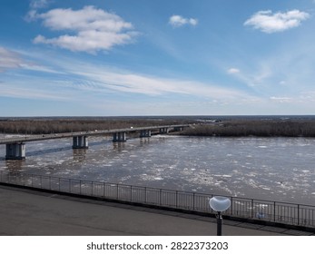 Bridge over river with ice drift spring landscape blue sky with light clouds flowing water seasonal thaw and urban nature scenery