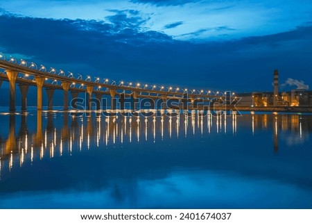 bridge over the river at night. bridge over the river. Sunset on blue sky with waterscape and lamps reflection on the water. industrial bridge with highway. illumination and light on the bridge. sea 