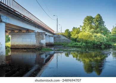 A bridge over a river with a train in the background. The bridge is old and has graffiti on it