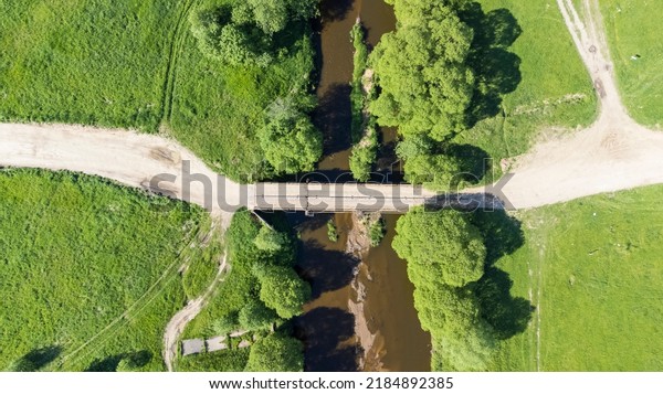 bridge over a small flat river on a sunny\
day view from a drone. High quality\
photo