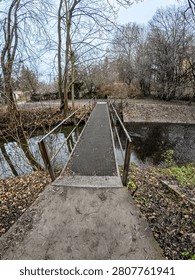 Bridge over a small stream in a forest setting, surrounded by trees, greenery, and a calm natural environment.