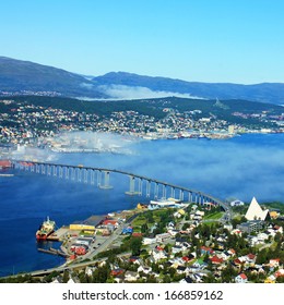 Bridge And Panorama Of City Tromso, Norway Beyond The Arctic Circle. View On Mountains In Norwegian Fjords.