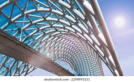 The Bridge of Peace is a bow-shaped pedestrian bridge, a steel and glass construction illuminated with numerous LEDs, over the Kura River, linking the Rike Park with Old town in central Tbilisi. - Powered by Shutterstock