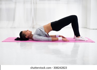 Bridge pose sporty woman doing warming up exercise for spine, backbend, arching stretching her back  working out at home fitness workout yoga gymnastics concept.