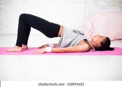 Bridge pose sporty woman doing warming up exercise for spine, backbend, arching stretching her back  working out at home fitness workout yoga gymnastics concept.