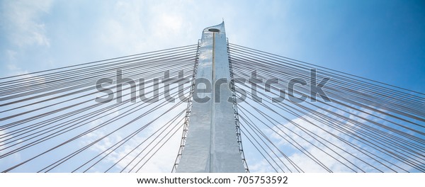 Bridge\
pylon with the hawsers on the blue sky\
background.