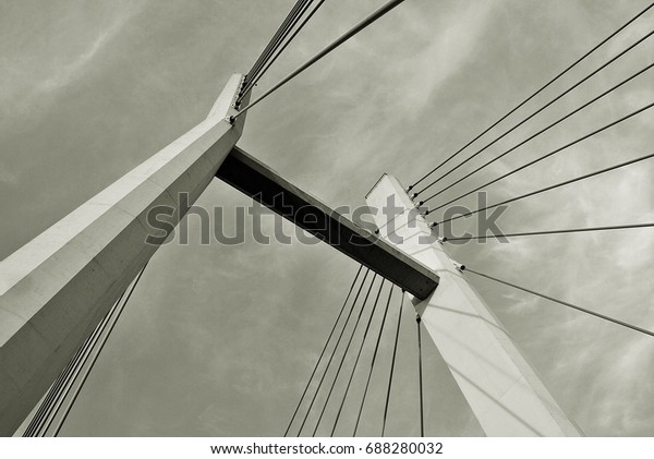 The bridge pylons on the ropes against the blue\
sky in the clouds.Black and\
white