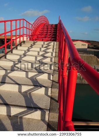 a bridge with a red fence and a small house with a bright and beautiful sky