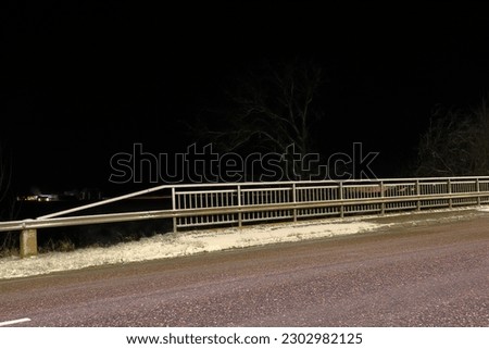 Bridge and road at a winter night. Safety fence at the side of the street.