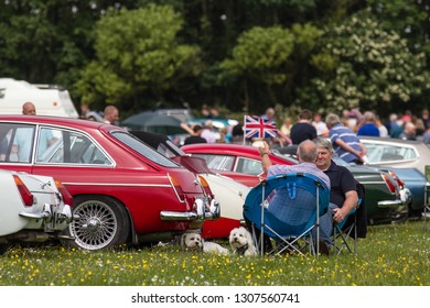 Bridlington / Great Britain - June 12, 2016: Scene At A Classic Car Show Festival Showing Two Caucasian Men Sat In Chairs Behind Classic Cars Talking, Two Sogs Beside Them.