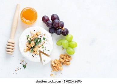 Brie or camembert cheese served with grapes, honey and walnuts on a marble table, top view, copy space - Powered by Shutterstock