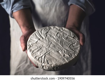 Brie cheese. Chef in a white apron holds whole round of cheese. French cheeses, rustic style - Powered by Shutterstock