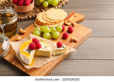 Brie cheese served with berries and honey on wooden table. Space for text