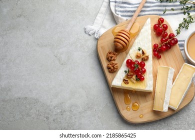 Brie cheese served with currants, walnuts and honey on light table, flat lay. Space for text