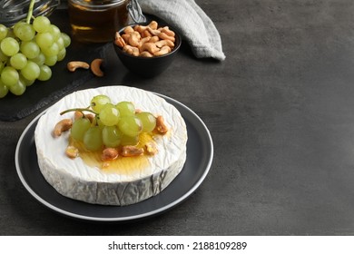 Brie Cheese Served With Grape, Cashew Nuts And Honey On Dark Grey Table. Space For Text