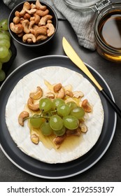 Brie Cheese Served With Grape, Cashew Nuts And Honey On Dark Grey Table, Flat Lay