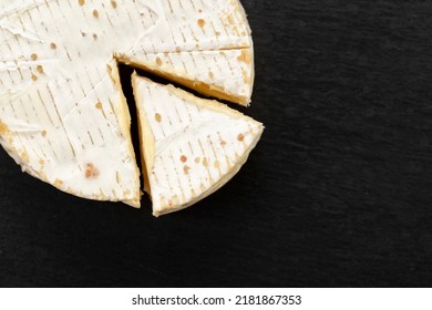 Brie type of cheese. Camembert cheese. Fresh Brie cheese and a slice on a black board. Italian, French cheese. Top view. - Powered by Shutterstock